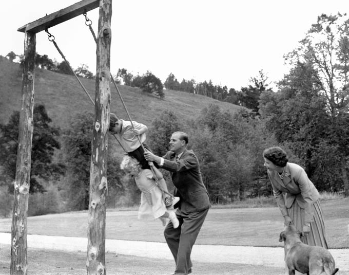 Prince Charles and Princess Anne being pushed on a swing by their father, the Duke of Edinburgh, with their mother Queen Elizabeth II looking on, in the grounds of Balmoral